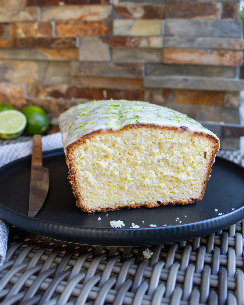 Lime Cream Cheese Pound Cake on black ceramic plate on a whicker table.