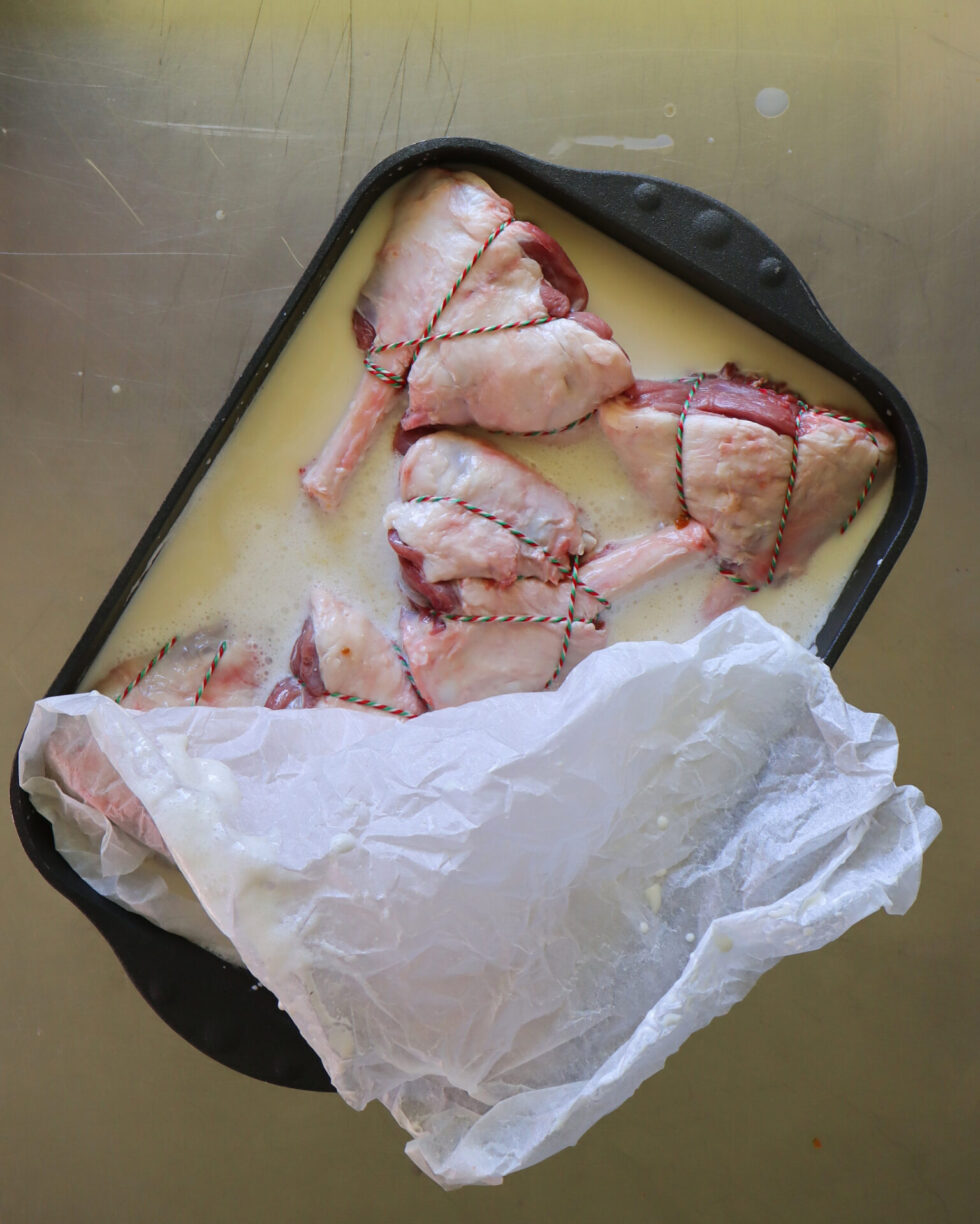 Ready for braising! A pan of trimmed and tied lamb shanks with a coconut cream mix and topped with a baking paper cartouche.