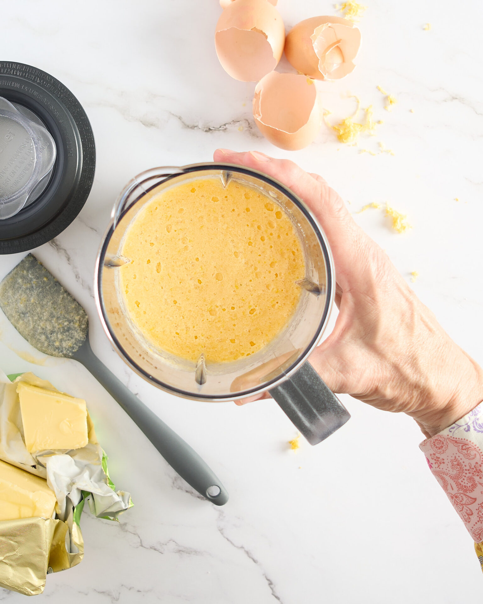 Cook shows emulsified lemon curd ingredients in a blender over a marble benchtop.