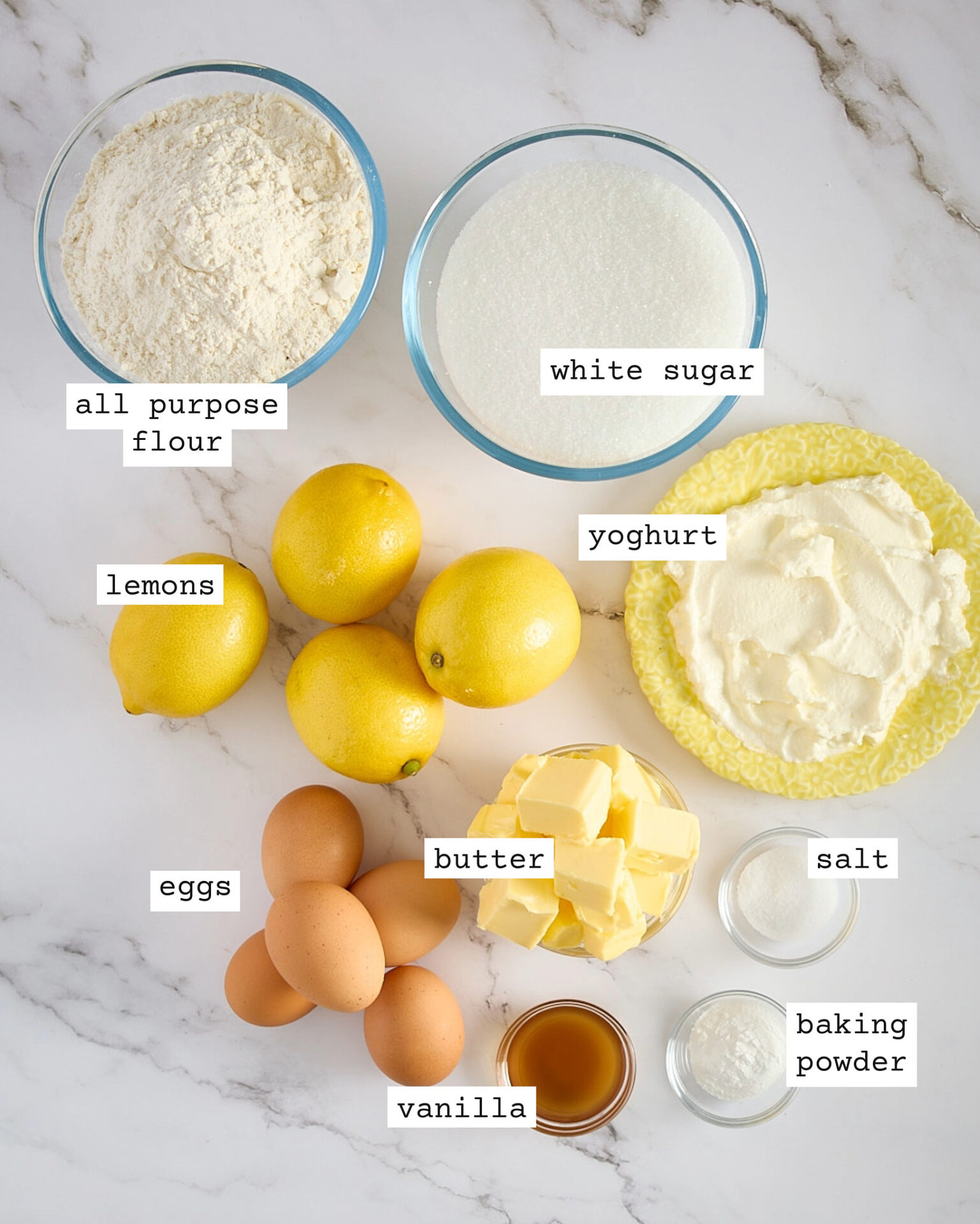 Labelled lemon sheet cake ingredients on a marble bench.