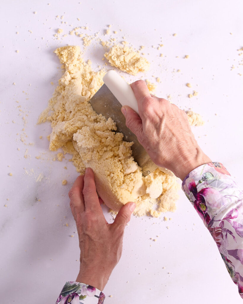 Cook scraping pastry by hand with a stainless steel pastry cutter.