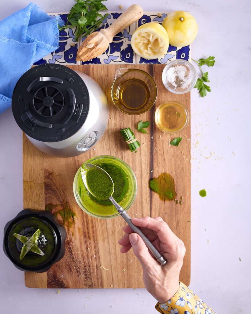 Sandra showing the vibrant colour and texture of the vinaigrette dressing fresh from the blender using a spoon.