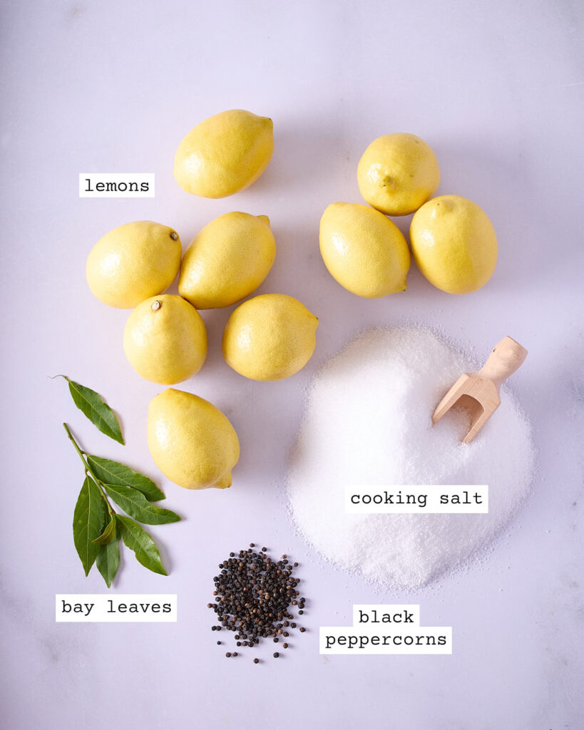 Labelled ingredients for easy Moroccan preserved lemons on a white marble bench.
