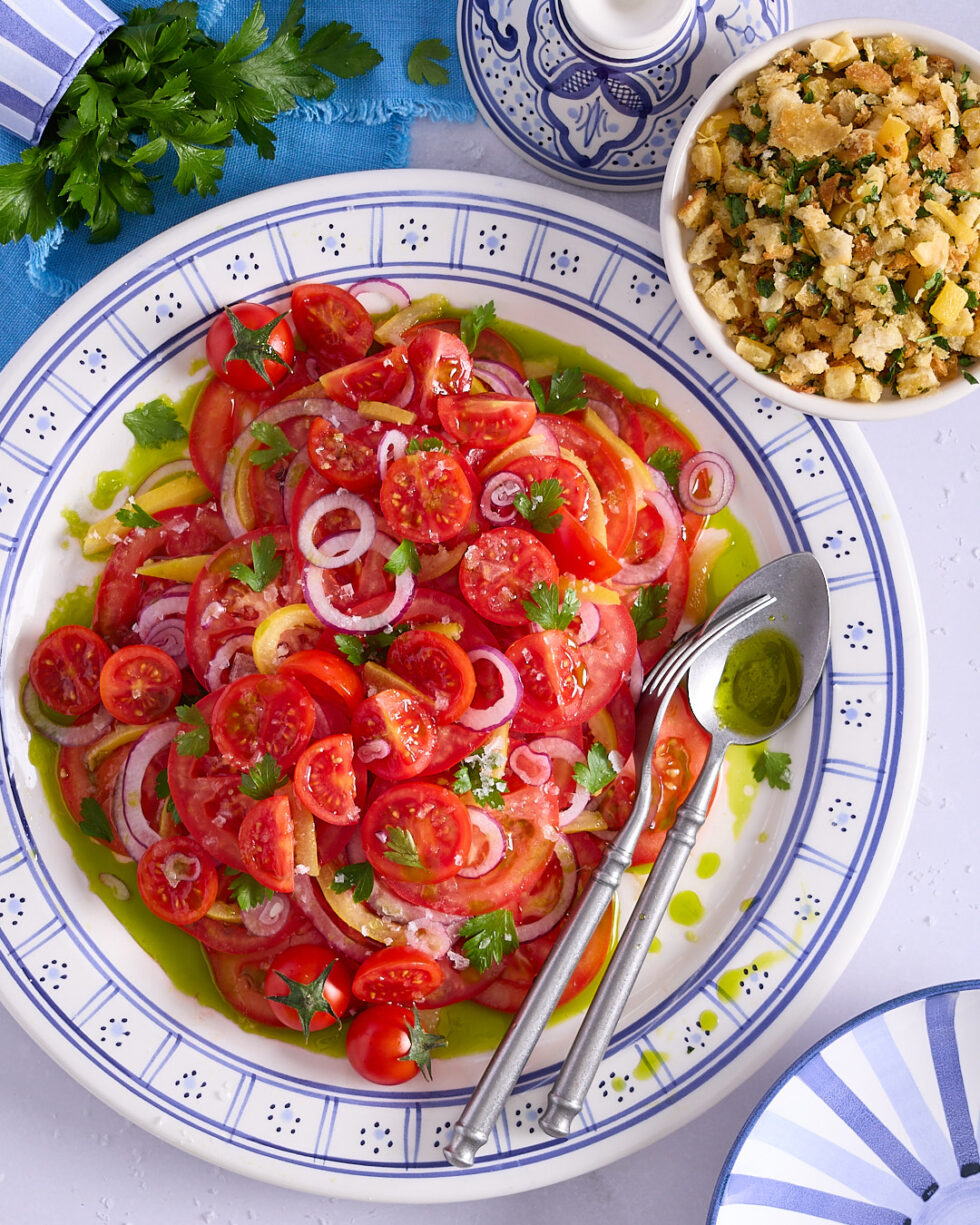 Tomato and preserved lemon salad served in a blue and white ceramic dish with a bowl of preserved lemon crumb nestle next to it.