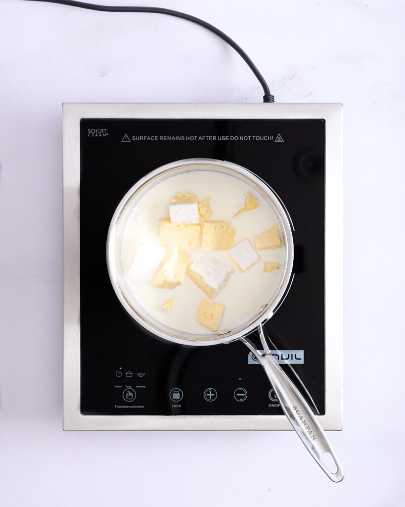 Brie cheese chunks melting into milk, in preparation for a triple cream brie cheese sauce.