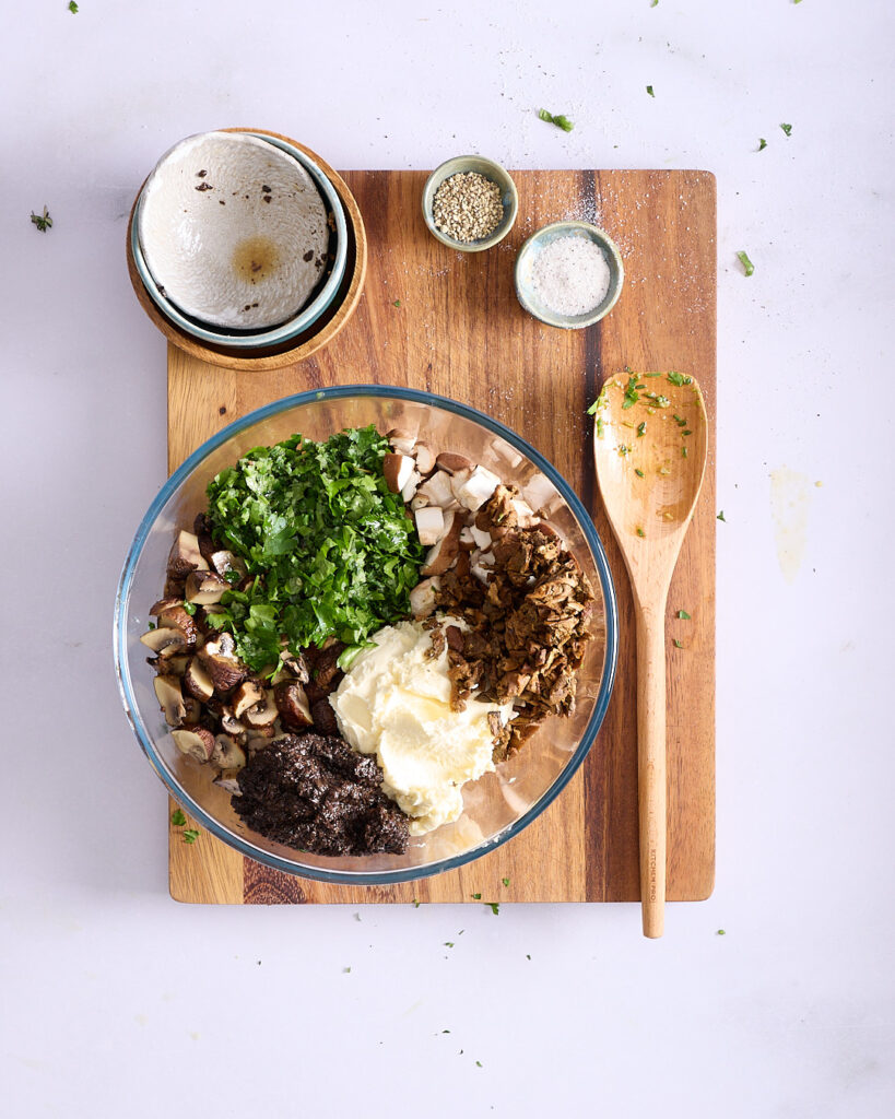 Chopped mushrooms, parsley, mascarpone, truffle salsa, and porcini mushrooms in a bowl.