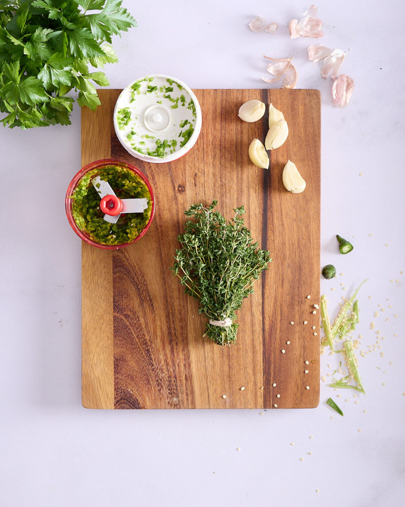 Chopped green chillies with garlic cloves, a bunch of thyme, and Italian parsley, ready to be sautéed.