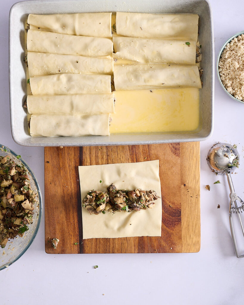 A generous serve of mushroom cannelloni with truffle, topped with toasted pine nuts, pickled red onions, and micro herbs. The creamy brie cheese sauce is golden and set, with green beans served on the side.