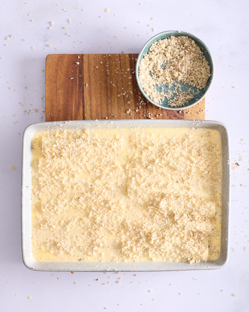 Fully assembled vegetarian truffle pasta bake sprinkled with truffle pecorino, ready for the oven.