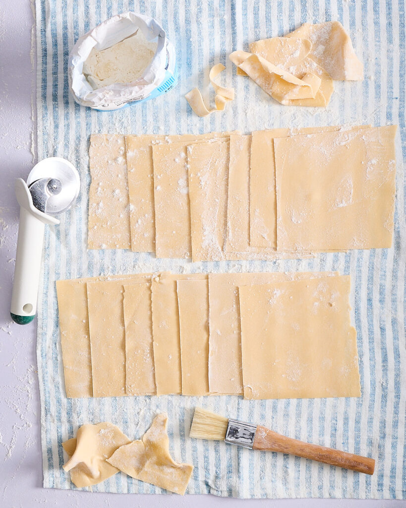 Homemade pasta sheets made with 00 flour, cut and drying on a tea towel—homemade egg pasta dough for homemade mushroom cannelloni.