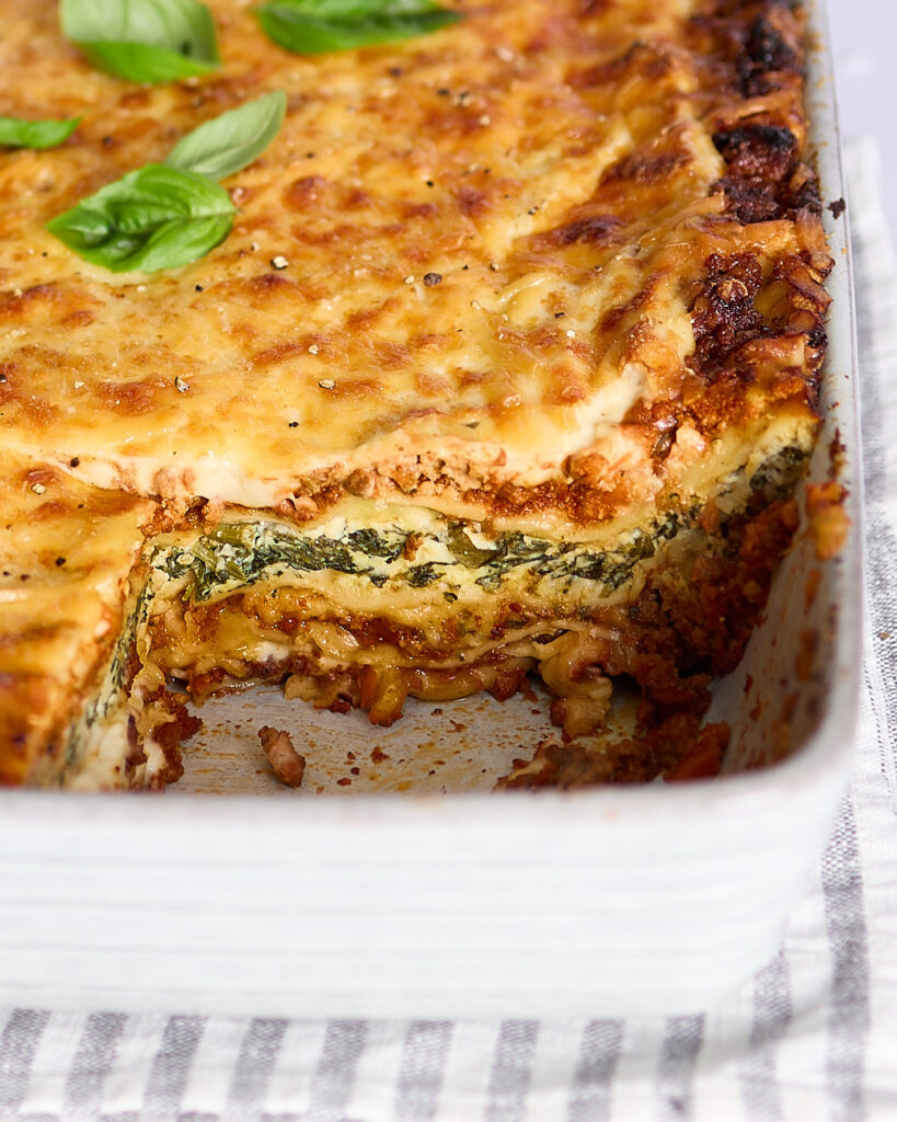 Closeup of a tray of my best lasagna with a slice served to show the rich layers inside.