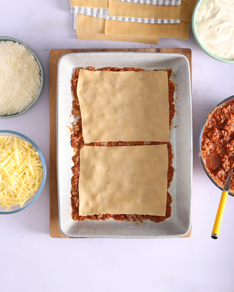 Fresh lasagna sheets layered over bolognese sauce.