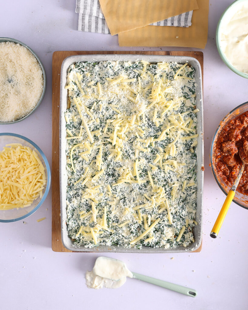 Spinach and cheese layer spread over fresh pasta sheets.