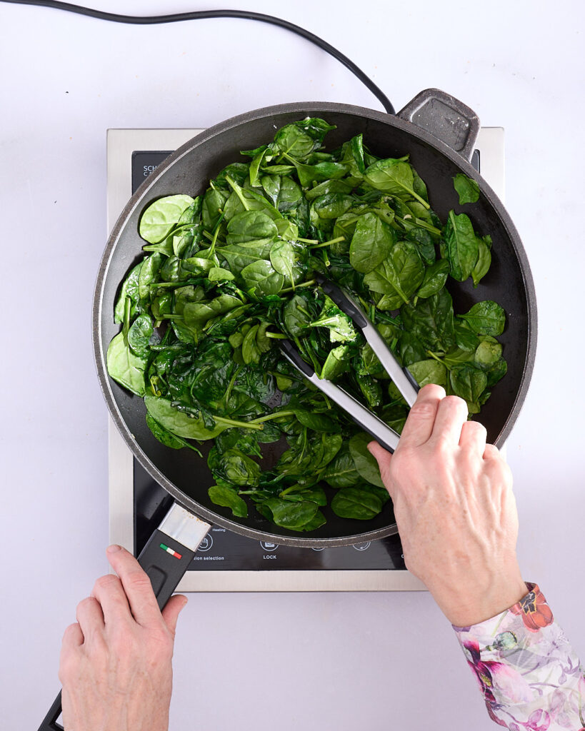Sandra wilting baby spinach to be cooled and chopped.