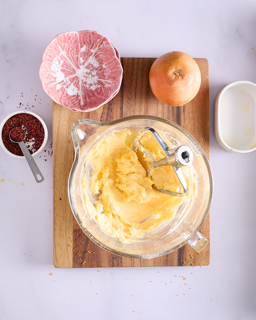 Creamed butter and sugar in a glass bowl attached to a stand mixer with a paddle attachment.