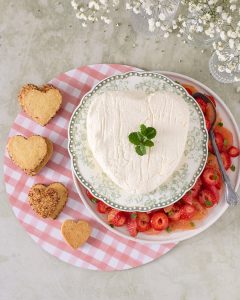 Heart shaped yoghurt coeur à la crème on a floral plate served with a pink peppercorn grapefruit and strawberry compote and botanical shortbread.