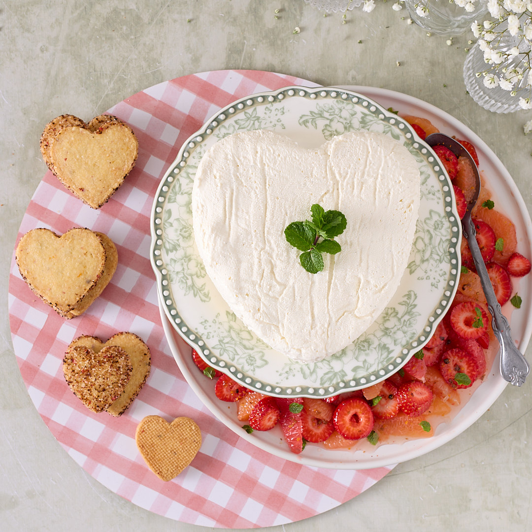 Heart shaped yoghurt coeur à la crème on a floral plate served with a pink peppercorn grapefruit and strawberry compote and botanical shortbread.