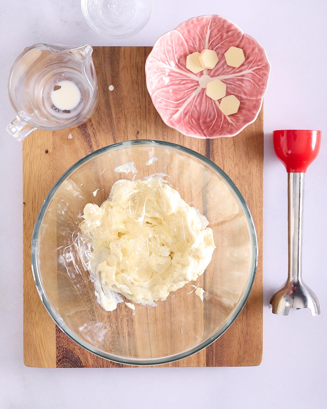 White chocolate pieces and glucose in a glass bowl with gelatine leaves before melting.