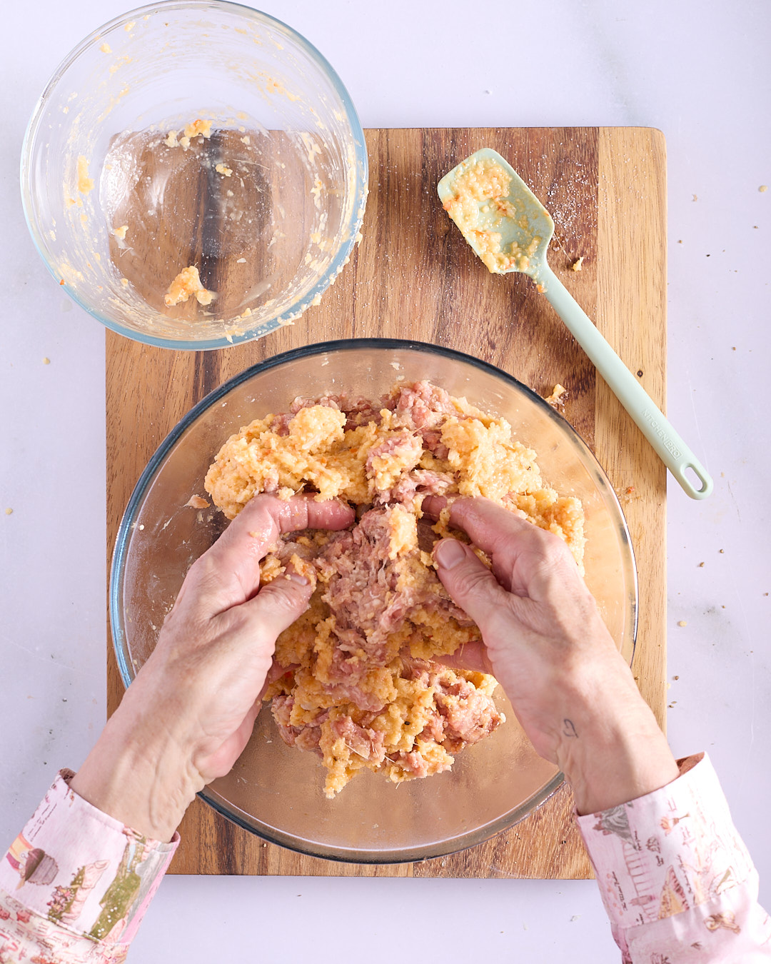 Sandra combining the aromatic breadcrumb and egg mixture through seasoned ground pork and chicken mince by hand for Vietnamese-style pork and chicken meatloaf filling.