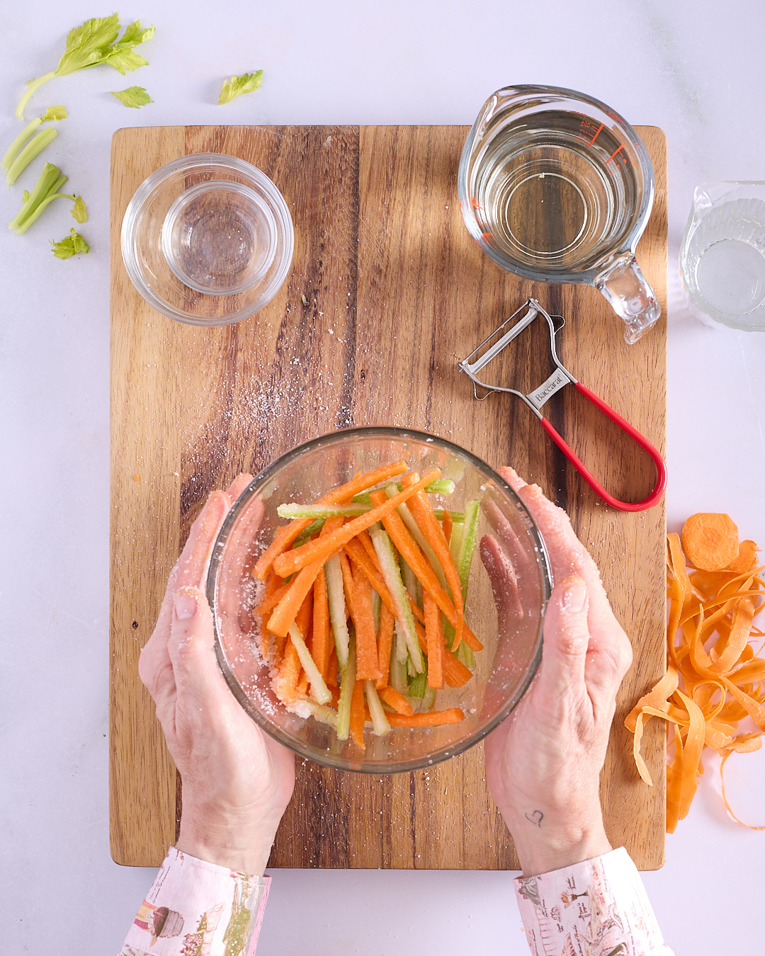 Sandra massaging sugar and salt into carrot and celery batons in a glass bowl as part of the quick pickle method for Vietnamese-style pork and chicken meatloaf bánh mì.